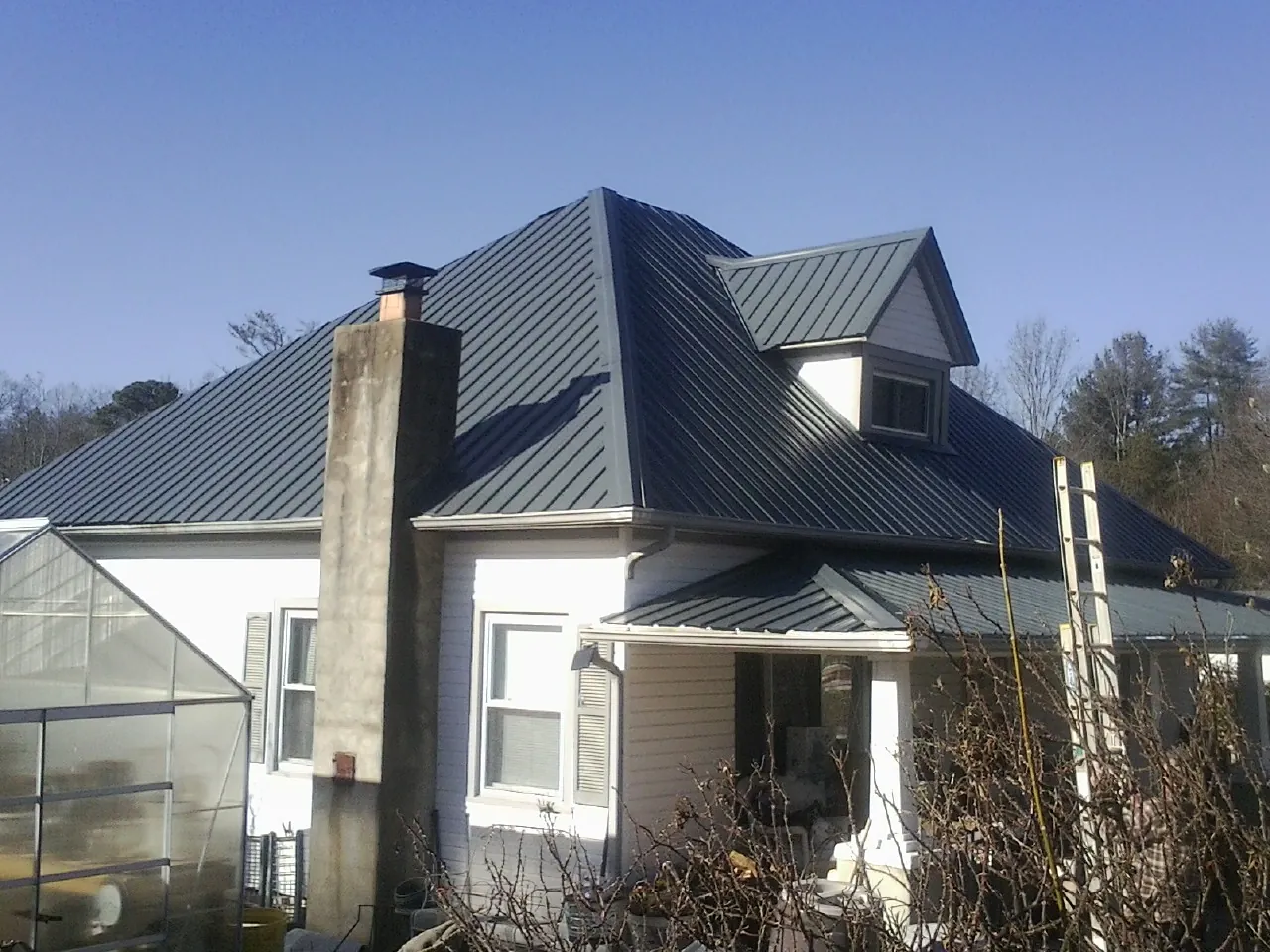 Dark blue standing seam metal roof on a white farmhouse with dormer — Slate & Tile Roof Repair by Roofing Brothers in Heber City