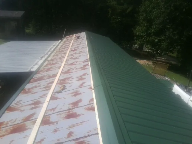 Old rusted panels beside newly installed green metal roofing — Wind Damage Roof Repair by Roofing Brothers in Heber City