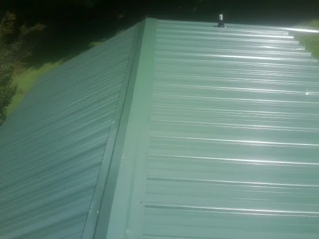 New green metal panels meeting at the ridge of a roof — Flat Roof Repair work by our crew in Heber City