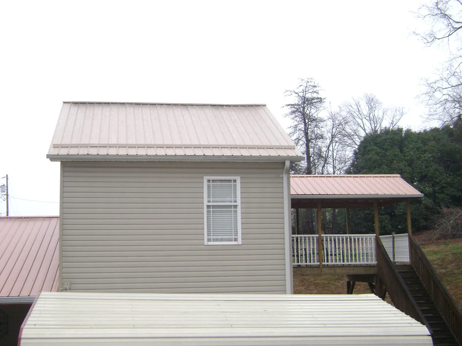 Tan metal roofs on a two story addition and attached porch, from a Roof Replacement job in Heber City