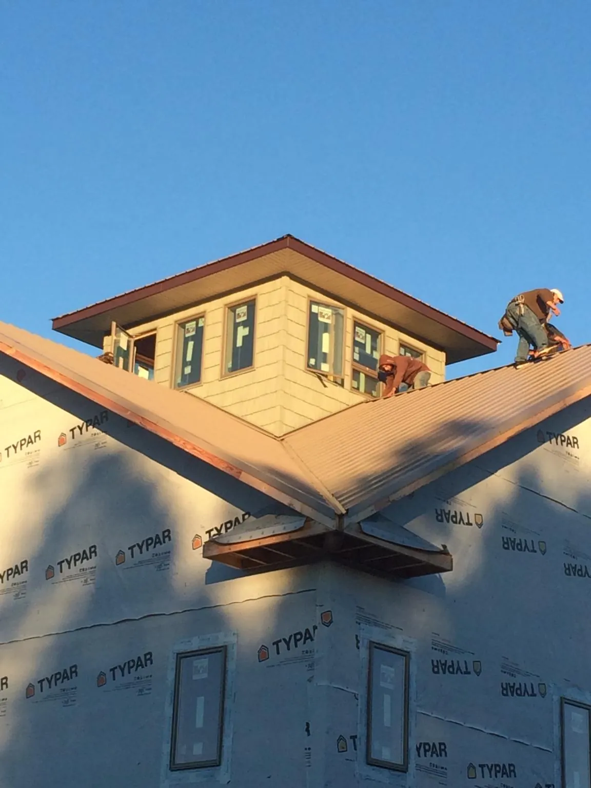 Roofers working around a rooftop cupola on a new metal roof at sunset — Roof Waterproofing in Heber City by Roofing Brothers